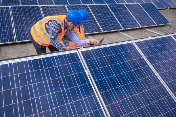 istock Rows of photovoltaic panels on flat roof, engineers setting up parameters in computer 1348372273
