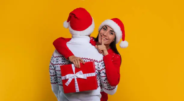 Photo of Close up photo of beautiful happy and excited young couple in love in Christmas clothes with gift boxes in hands while they celebrating New Year and giving presents yo each other