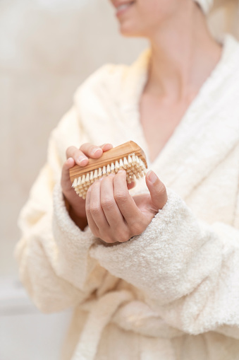 Young beautiful woman getting out of shower taking care of her hands with nail brush