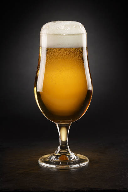 istock Mug with fresh beer with cap of foam on a black. 1348377988