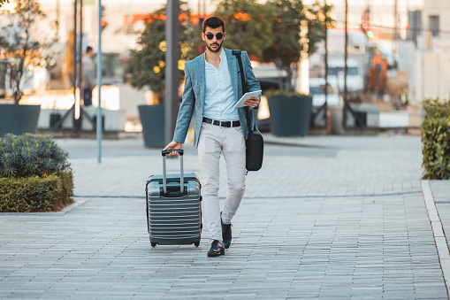 Young businessman with a suitcase and a tablet in his hand, rushes to the plane.