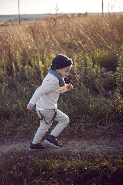 istock boy in warm clothes runs along a path on a field with dried grass 1348383829