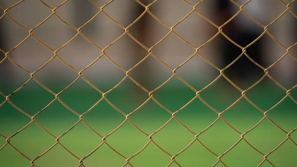 primo piano della vecchia recinzione a catena in un campo da calcio. - topics barbed wire fence chainlink fence foto e immagini stock