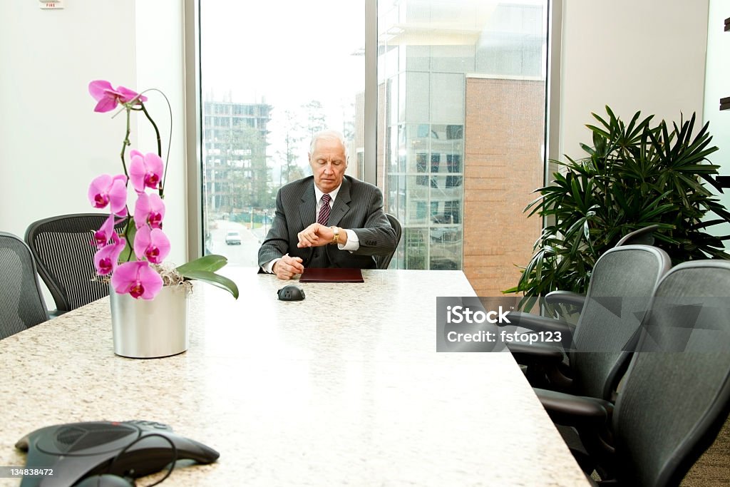 Executive in conference room Executive in third floor conference room checking his watch. Active Seniors Stock Photo