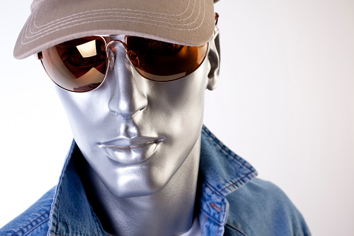 Mannequin in denim, ball hat and sun glasses, head and shoulders close-up.