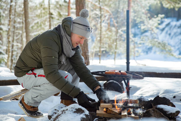 istock Man roasting sausages on campfire in forest by the lake 1348386202