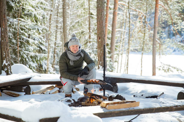 istock Man roasting sausages on campfire in forest by the lake 1348386203