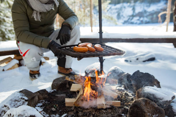 istock Man roasting sausages on campfire in forest by the lake 1348386204