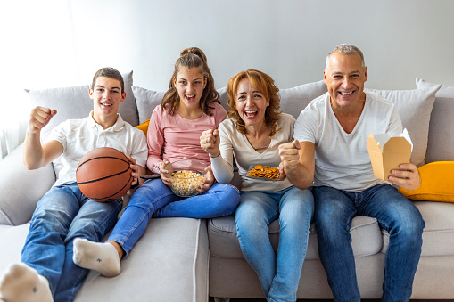 Family with children cheering and watching Basketball game on TV
