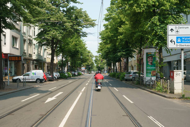 Dusseldorf, Germany - June 3, 2019: Everyday city life. Traffic. Cable car road, cars on the city street. Parked bikes and cars. Motorcyclist on the road. Lifestyle concept.