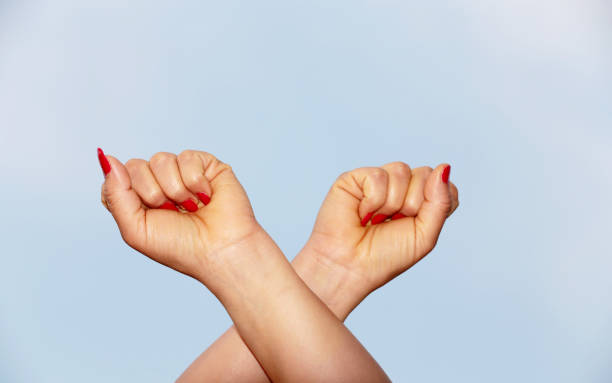 Female hand crossed against blue background.
