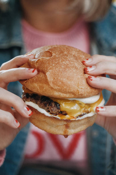 istock a girl holding hamburger with her hands 1348389446