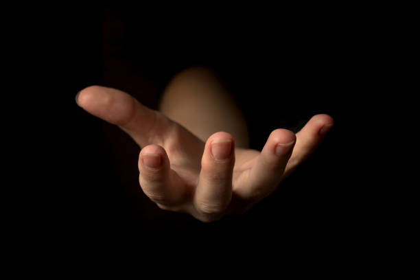 Hand gesture on a black background, palm up holding something, mockup and template for presentation concept