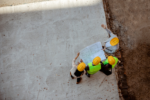 Top View of Architects and Engineer Workers With Blueprints Discussing at Construction Site
