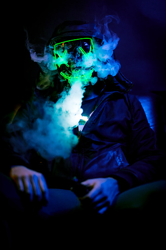 A man sitting with a halloween mask. Various poses in the dark.
