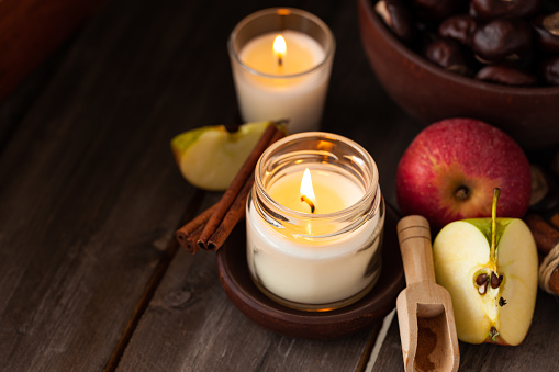 Composition with aromatic candles, apple, cinnamon, chestnut. Cozy home atmosphere, aromatherapy. Dark wooden background