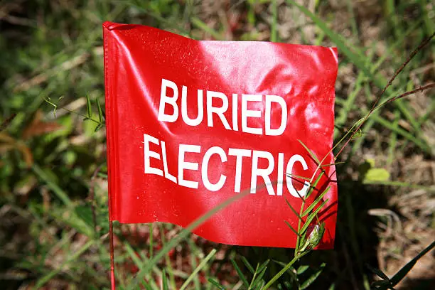 Photo of Buried electric cable flag staked in ground. Red.