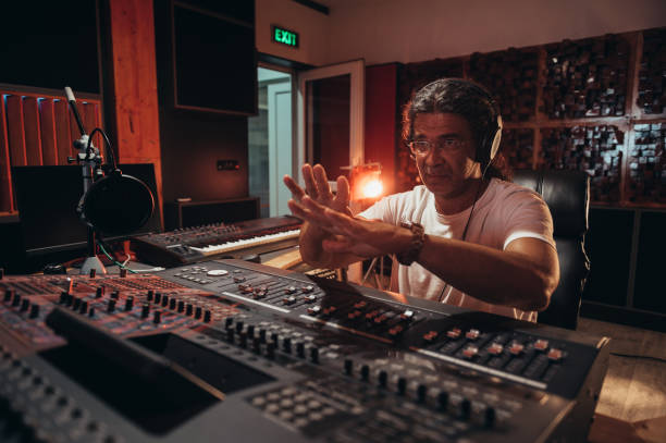 istock Senior hispanic music producer working on a mixing soundboard while in his studio 1348415528