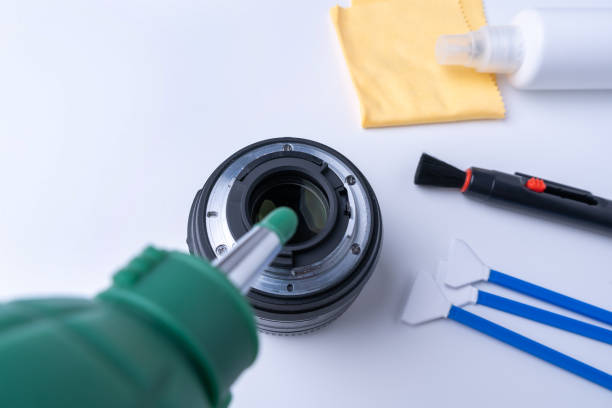 istock Photographer blows bullets from the camera lens. Camera cleaning accessories on white background 1348423837