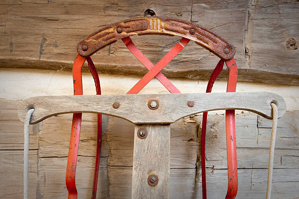 A close-up of an antique sled leaning up against a log wall.