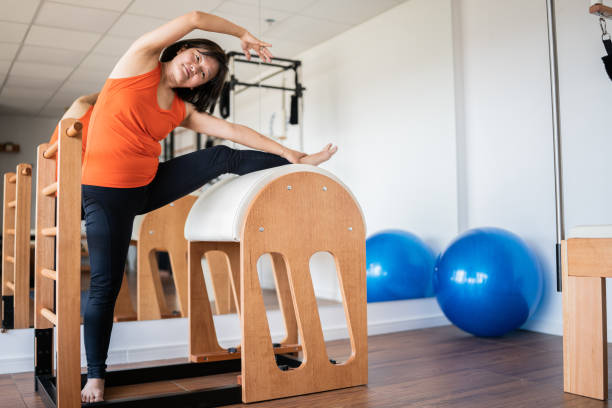 istock Mature woman stretching on barrel at pilates studio 1348459794