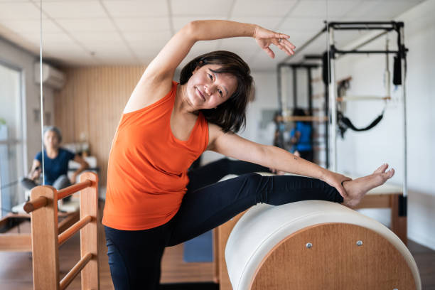 Mature woman stretching on barrel at pilates studio