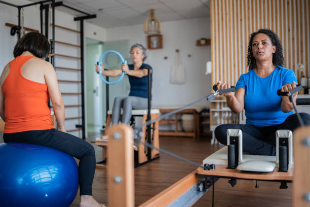 reife frauen trainieren in einem pilates-studio - physical therapy exercise machine exercising exercise equipment stock-fotos und bilder