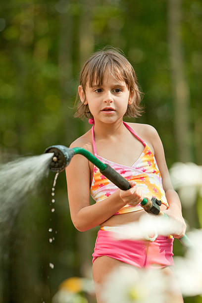istock Girl waters the lawn from a hose 134846194