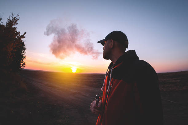 istock The man smoke an electronic cigarette on the sunset backround 1348475640