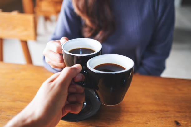 istock a man and a woman clinking coffee mugs in cafe 1348516093