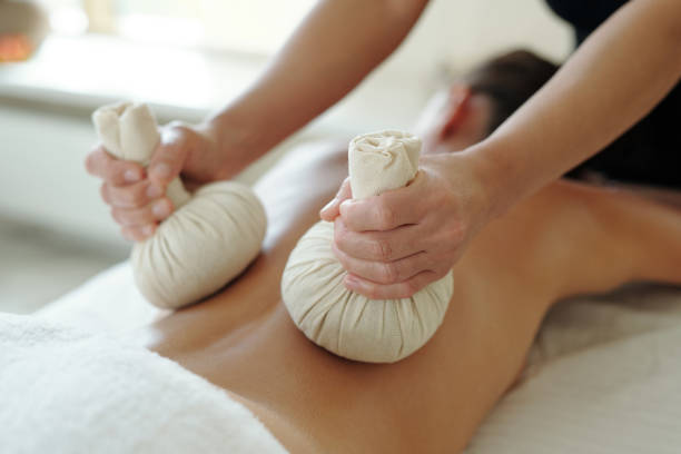 istock Masseuse pressing back of female client with two herbal compress balls 1348534002