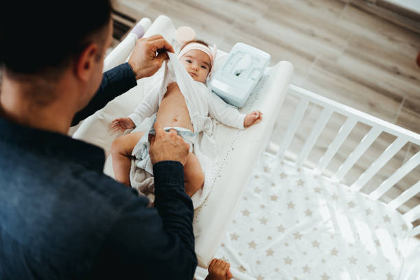Dad changes the baby's diaper stock photo