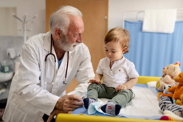 istock Doctor playing with baby boy on the table in doctors 1348538378