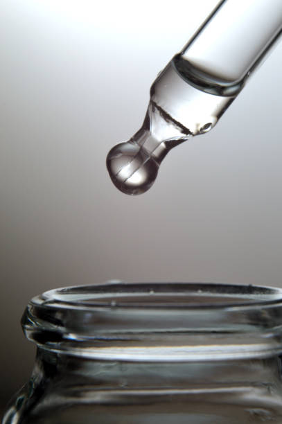istock Liquid transparent gel or serum pipette with drops on gray background 1348541047