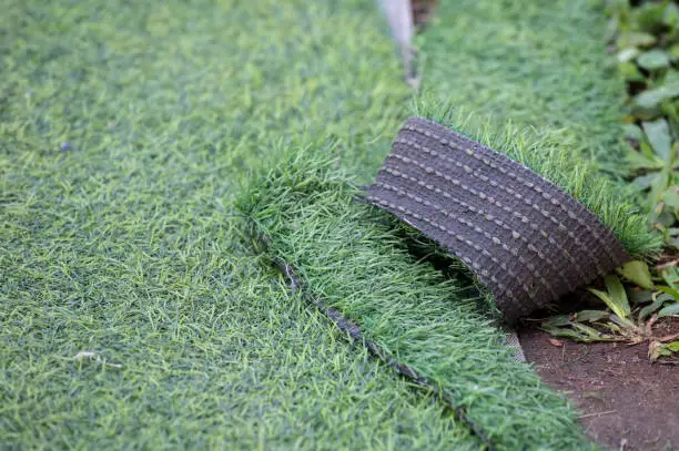 Photo of Green artificial turf used for covering sport arena or garden.