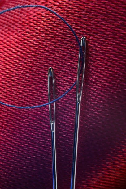 istock two sewing needles with blue thread on a background of red fabric. close-up. 1348544366