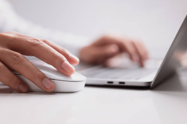 istock Male hand holds a computer mouse and typing laptop keyboard. 1348544567