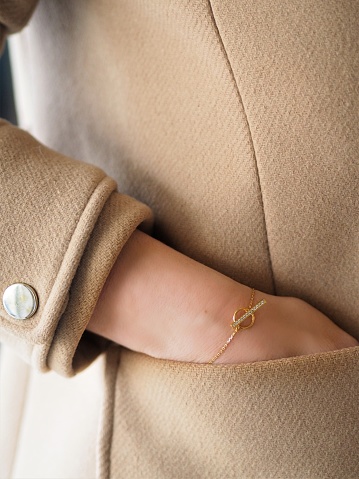 Diamond and Gold bracelet on a woman wrist on a camel coat