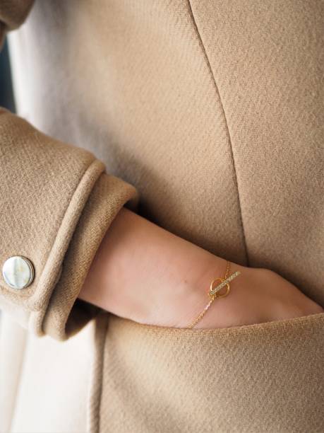 Diamond and Gold bracelet on a woman wrist on a camel coat stock photo