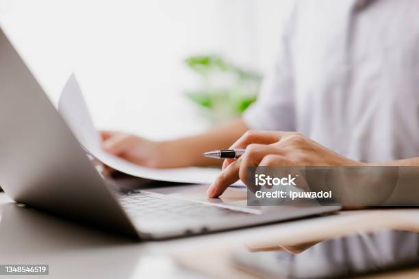 Businessman Hand Is On The Trackpad Typing On A Laptop Keyboard While Reading A Business Document In A Modern Office A Corporate Man A Lawyer Works Concept Of Business And Technology Stockfoto en meer beelden van Document