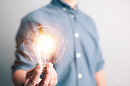 Man holding light bulbs, brainstorming new ideas innovation technology and creativity. Glittering bulbs with a creative idea.