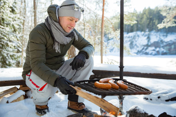 istock Man roasting sausages on campfire in forest by the lake 1348553079