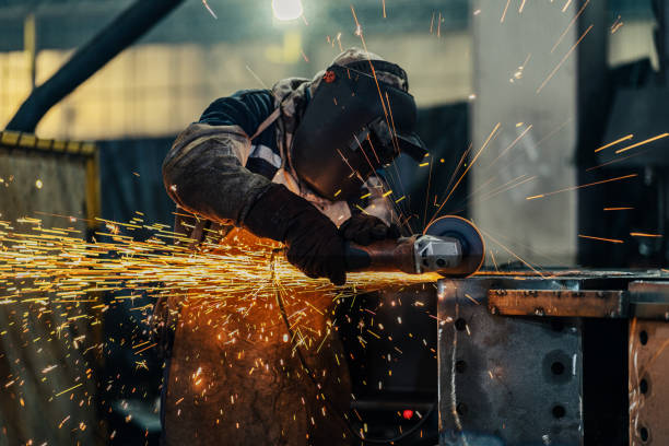 operaio metalmeccanico che usa una smerigliatrice - welding metal manufacturing industry foto e immagini stock