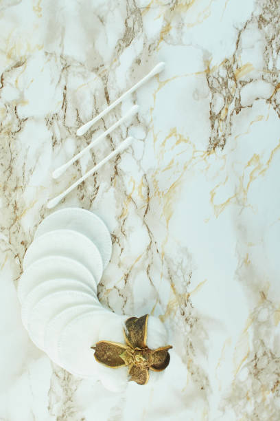 istock Cotton flowers with soft makeup pads on marble texture background. 1348572657