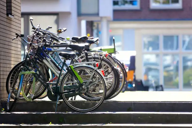 Photo of Artistic City View - parked bicycles against the backdrop of residential buildings. Beautiful morning light.  Urban life of a modern European city. Amsterdam, Holland, Europe