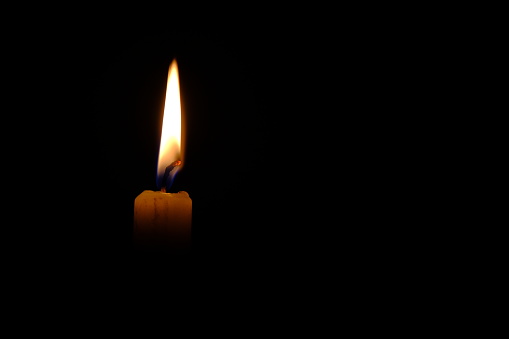 Single candle, candle made of wax and fire with black ground.