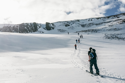 A group of climbers ascending snow-covered mountains in winter hiking in the  in Iceland. People extreme activities sports concept image.