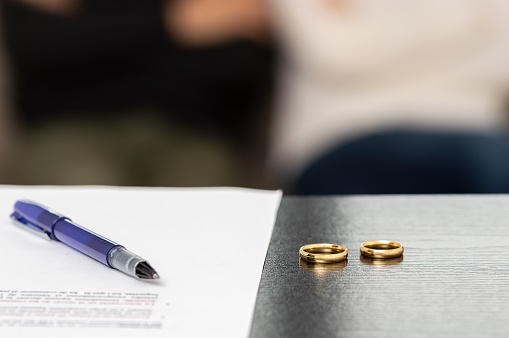 Document of a decree of divorce, dissolution, annulment of the marriage along with some wedding rings. Documents of legal separation, presentation of divorce papers or prenuptial agreement.