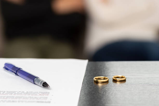 signing the divorce Document of a decree of divorce, dissolution, annulment of the marriage along with some wedding rings. Documents of legal separation, presentation of divorce papers or prenuptial agreement. divorce stock pictures, royalty-free photos & images