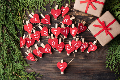 Handmade heart-shaped advent calendar on a wooden background, preparation for Christmas, close-up.